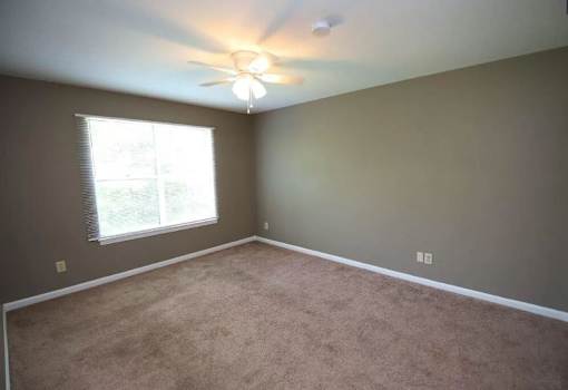 A room with a ceiling fan and a window with blinds.