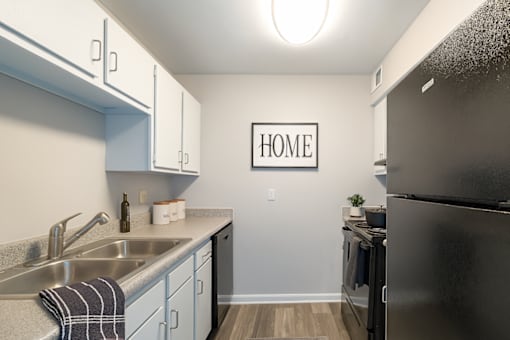 A kitchen with a black refrigerator and a sign that says "HOME".