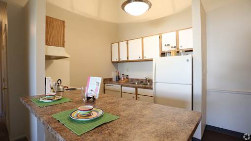 A kitchen with a table set for two with a green placemat and plates.
