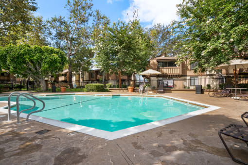 a swimming pool with trees and a building in the background