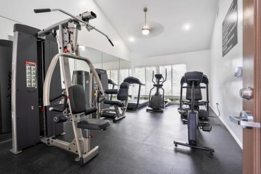 a gym with weights and cardio equipment on the floor and a window