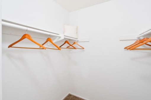 a white closet with orange hangers and white walls