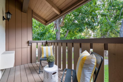 a covered porch with two chairs and a table