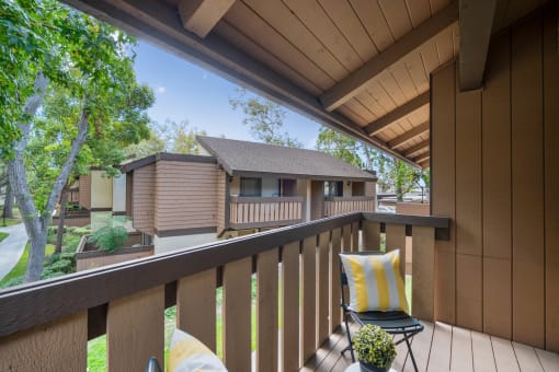a balcony with two chairs and a house in the background