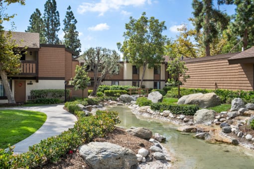 a pond in front of a building with trees and rocks