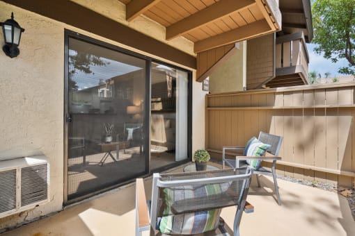 a patio with two chairs and a table and a sliding glass door