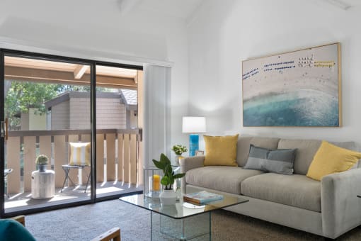 a living room with a couch and a glass coffee table and a sliding glass door