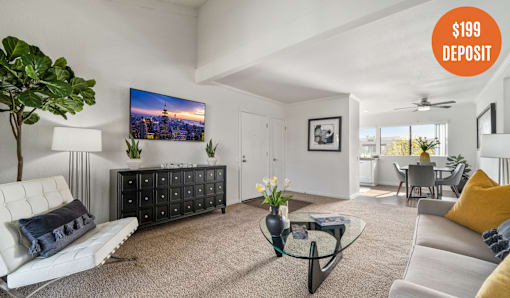 A living room with a white sofa, a black cabinet, and a TV displaying a cityscape.