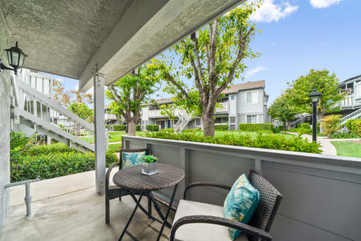 a patio with two chairs and a table on a balcony