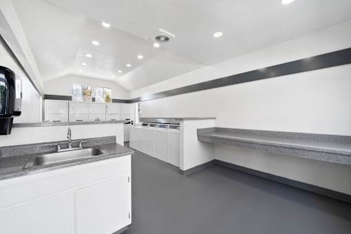 A modern kitchen with white cabinets and a grey floor.