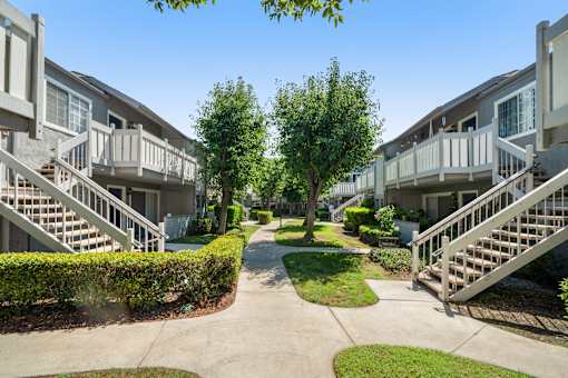 A sunny day at a residential complex with a pathway and greenery.