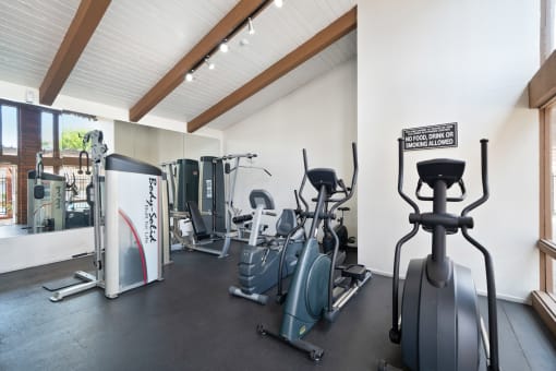 a gym with cardio equipment and weights on the floor