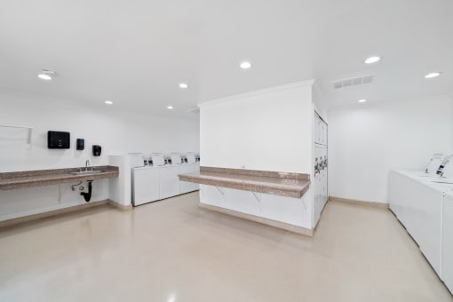 a kitchen with counters and sinks in a white room