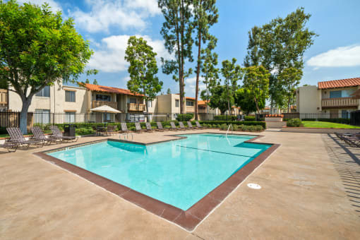 a swimming pool with trees and apartments in the background