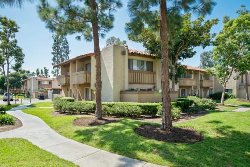 an apartment building with palm trees and a sidewalk