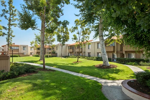a view of the grounds of an apartment building with grass and trees