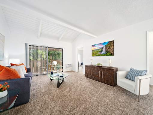 A living room with a sofa, a chair, a coffee table, and a painting on the wall.