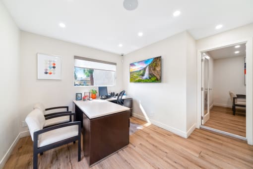a home office with a desk and chairs and a window