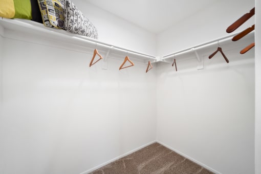 a walk in closet with white walls and a white shelf