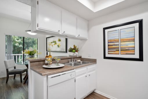a kitchen with white cabinetry and a white dishwasher