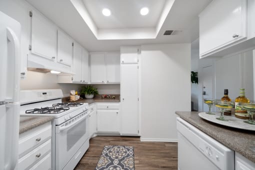 a kitchen with white cabinetry and a white stove top oven