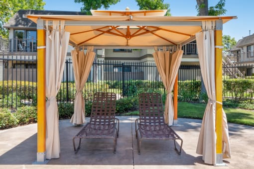 a pergola with two lounge chairs under it