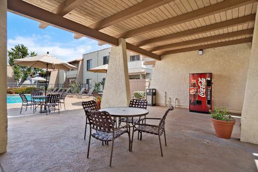 A patio with a table and chairs and a Coca-Cola machine.