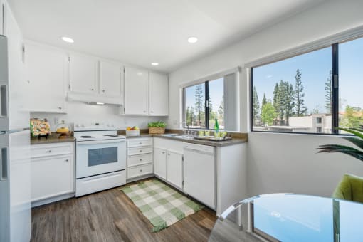 a white kitchen with a table and a large window