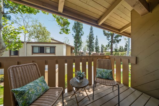 two chairs on a deck with a house in the background