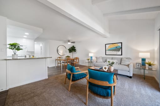 a living room with white walls and a white couch with blue chairs