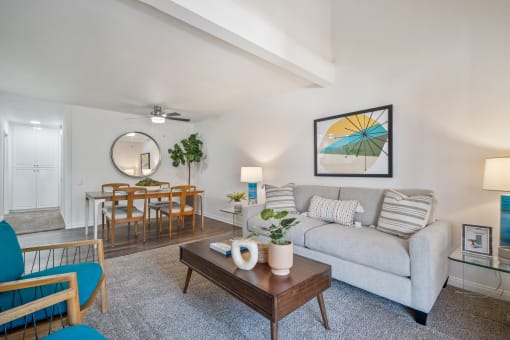 a living room with a couch coffee table and chairs and a dining room table in the background