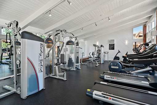 A gym with a variety of equipment including treadmills, weights, and exercise machines.