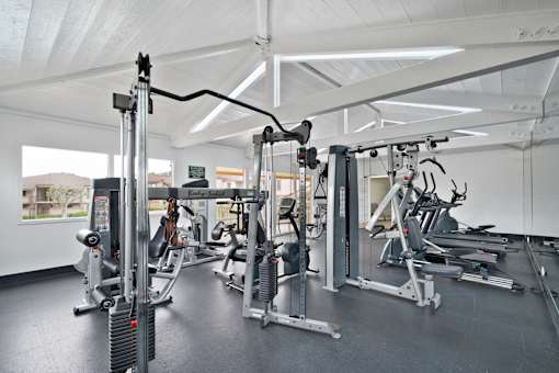 A gym with a variety of equipment including a weight machine, a treadmill, and a stationary bike.