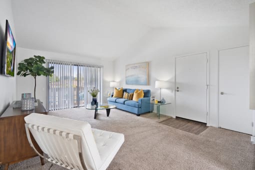 a living room with a blue couch and a white chair