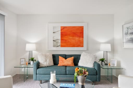 a living room with a blue couch and a orange painting on the wall