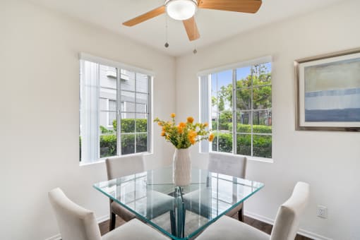 a dining room with a glass table and chairs and windows