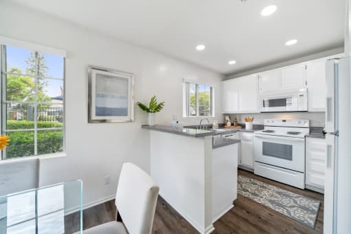 a white kitchen with white appliances and a table and chairs