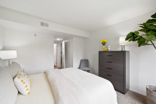a bedroom with a large white bed and a dresser