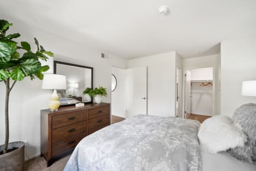 a bedroom with a large bed and a dresser with a mirror