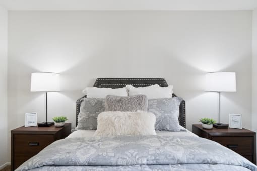 a bedroom with a large bed with pillows and two lamps