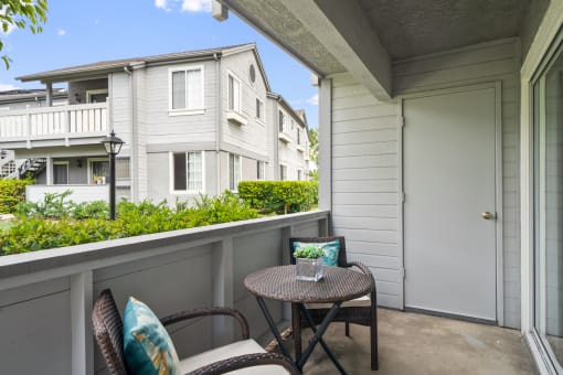 a patio with two chairs and a small table on a balcony