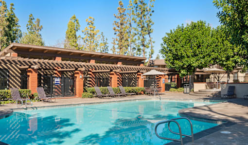 A swimming pool in front of a building with a red tiled roof.