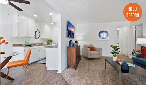 A living room with a kitchen area in the background and a $199 deposit sign.