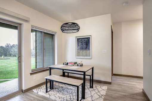 A black and white rug sits under a table in a room with a window.