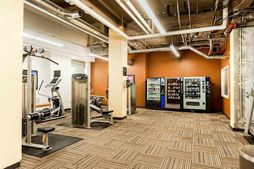 A gym with orange walls and a variety of equipment.