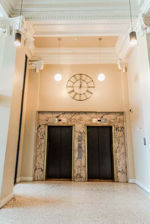 A clock hangs on a wall above two black doors.
