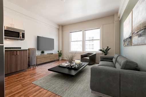 A modern living room with a grey couch, a coffee table, and a large window.