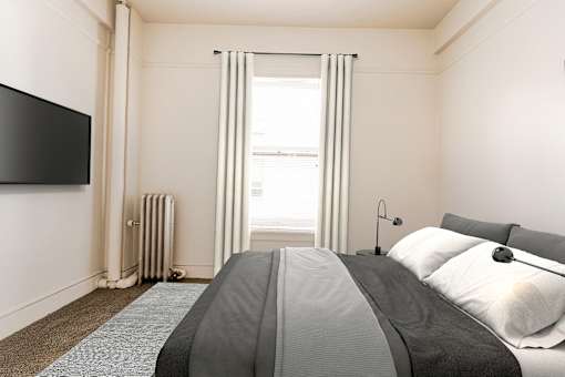 A bedroom with a large bed and a flat screen TV mounted on the wall.