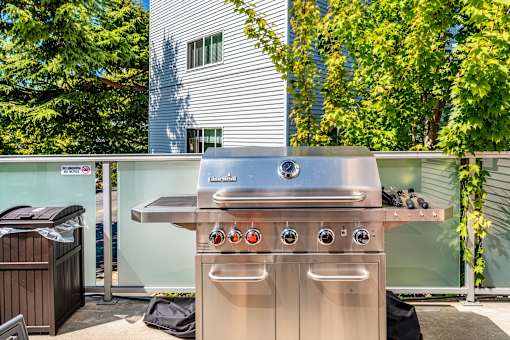 A stainless steel outdoor grill with four burners and two ovens is on a patio.