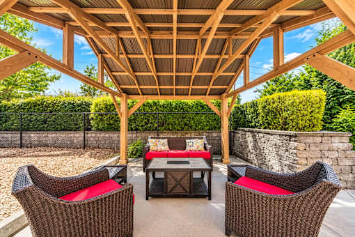 A wooden pergola with a table and chairs underneath it.